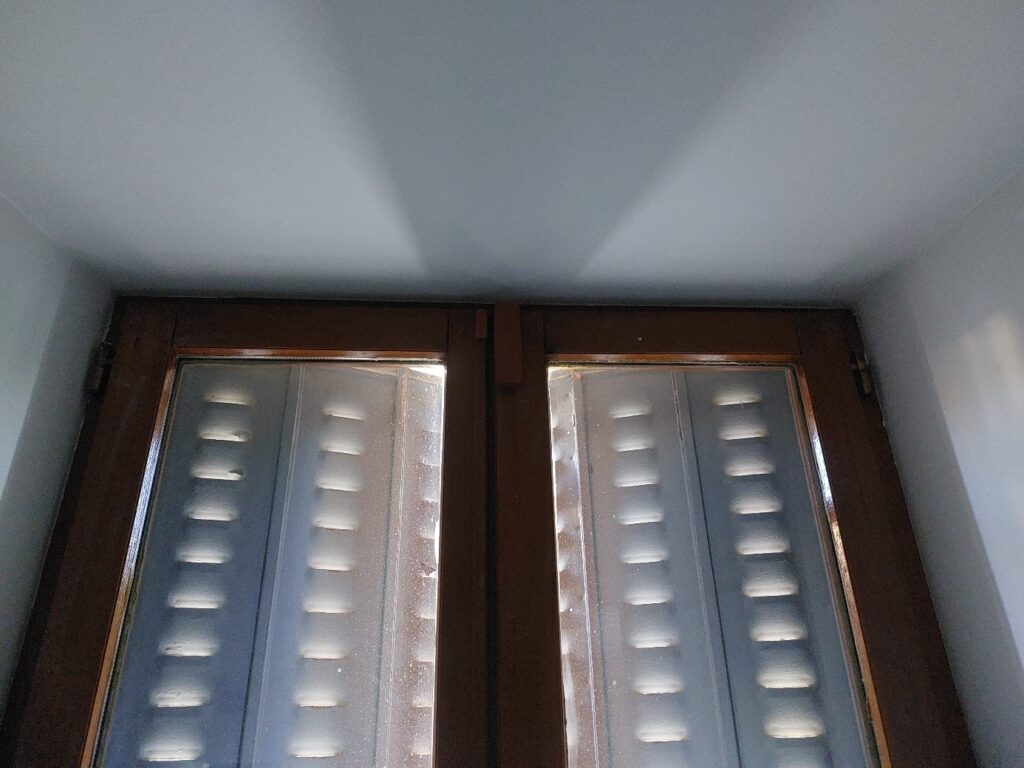 Détail rapproché du contacteur et de l’aimant du détecteur d’ouverture, fixés sur la menuiserie en bois