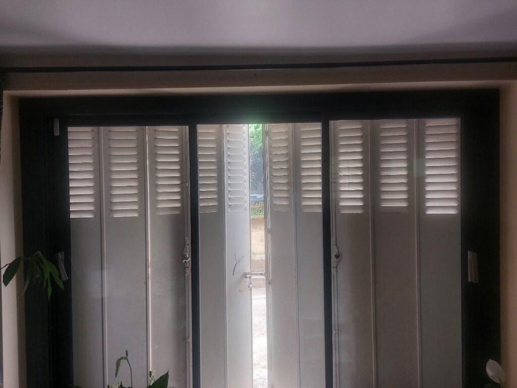 Détecteur d’ouverture d’alarme blanc, contrastant fortement sur l’encadrement noir d’une porte-fenêtre