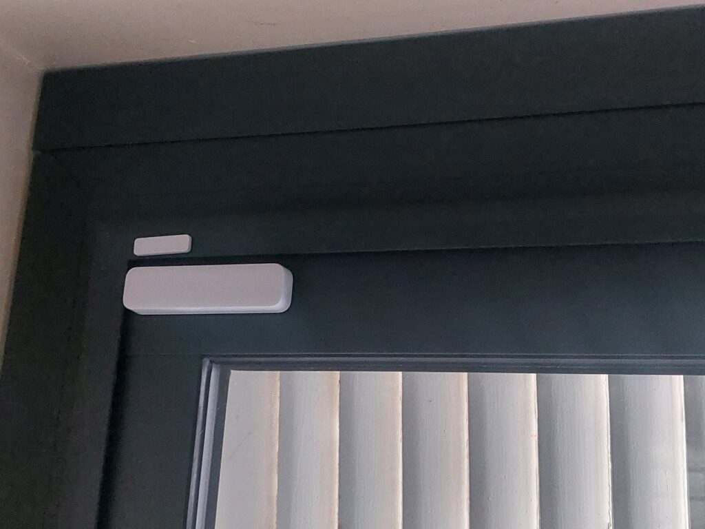 Détail rapproché du cache contacteur imprimé en 3D, une fois installé sur l’encadrement noir de la porte-fenêtre